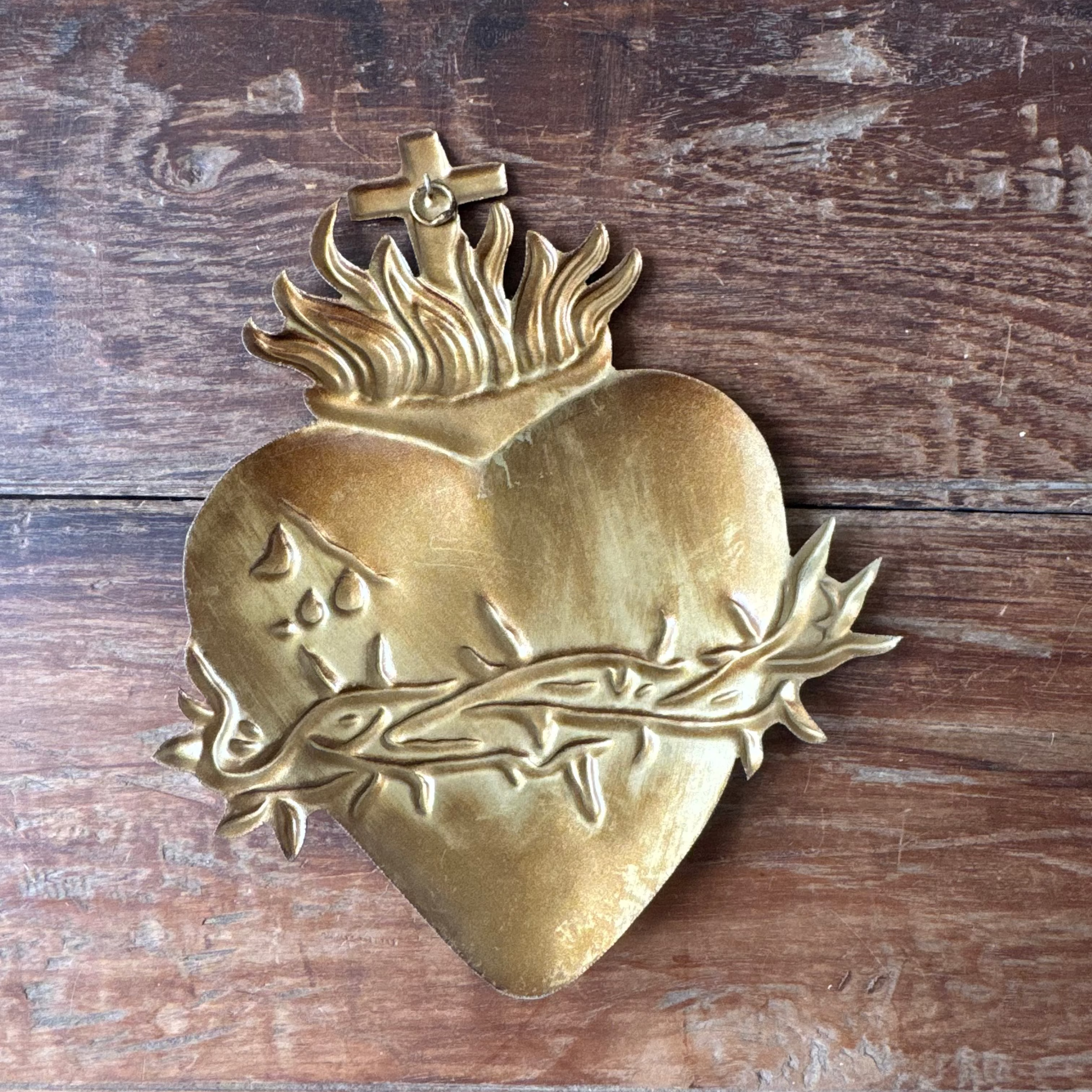 Brass Sacred Heart decoration on a wooden background