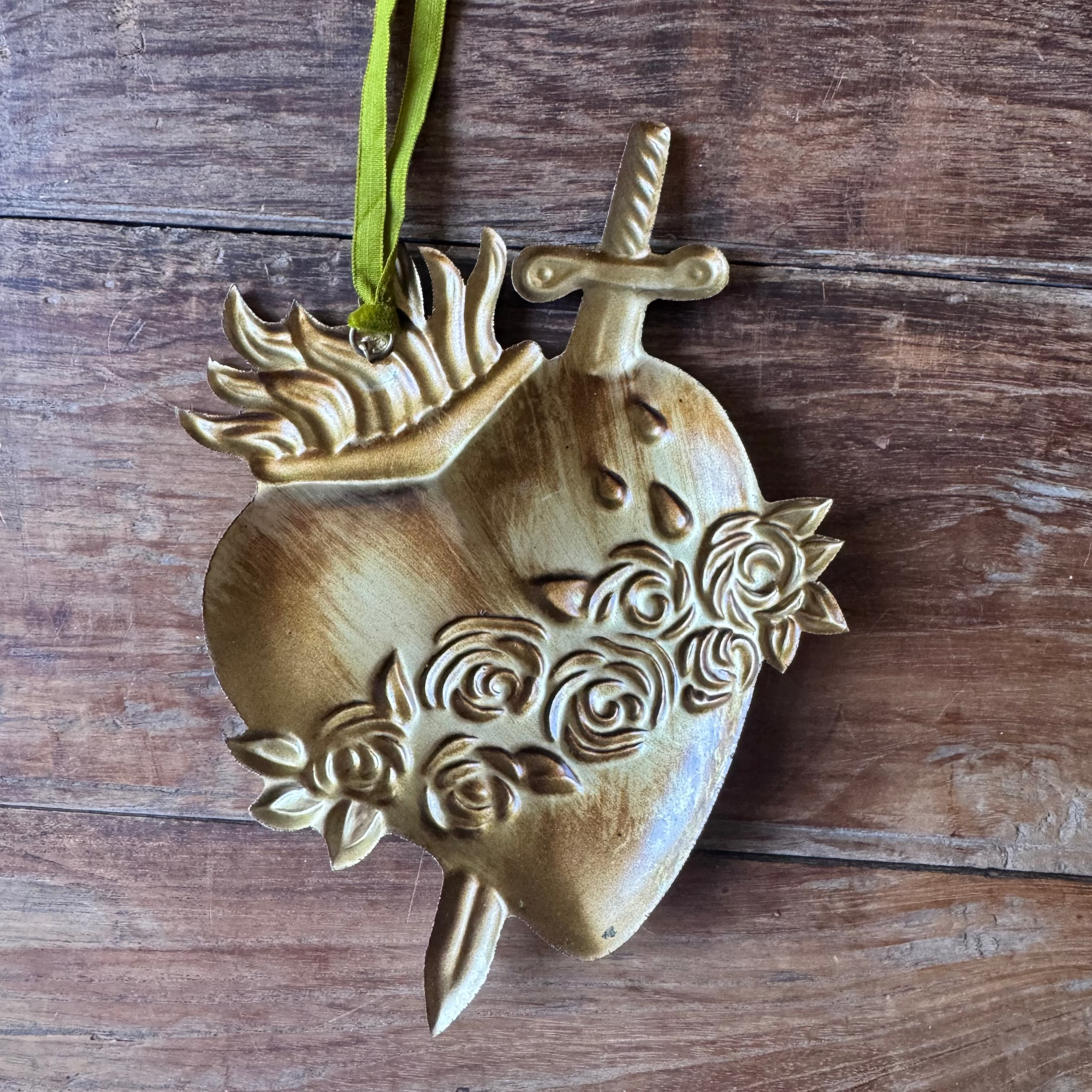 Decorative heart-shaped ornament with floral designs on a wooden surface