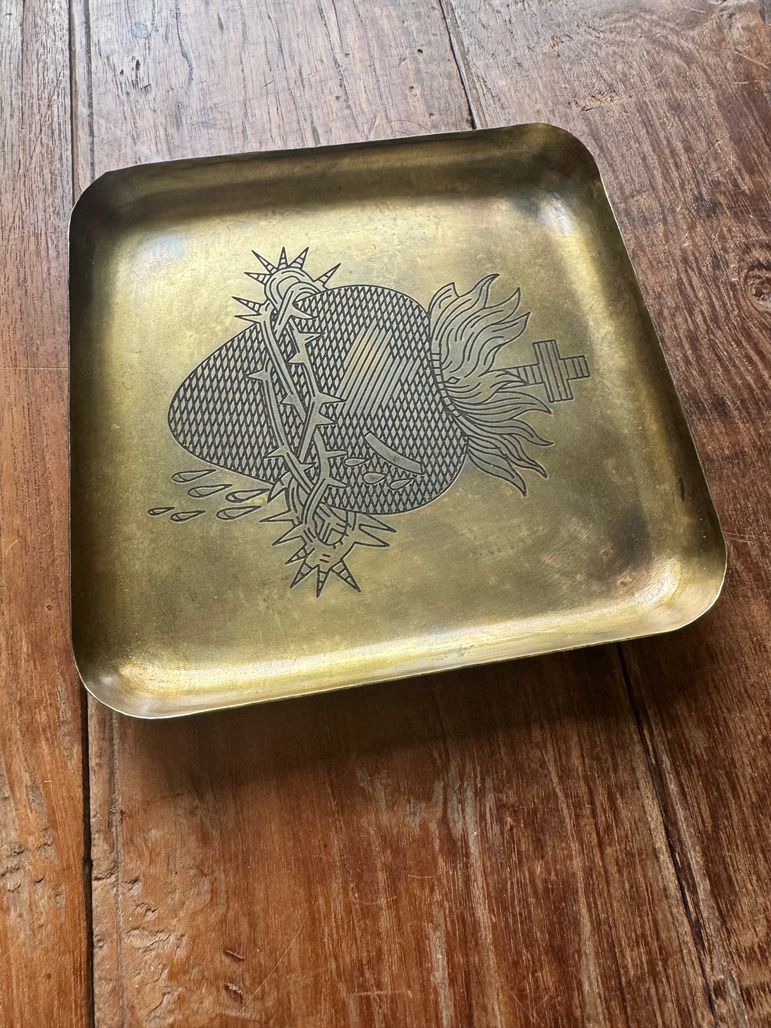 Brass tray with engraved Sacred heart of Jesus design on a wooden surface