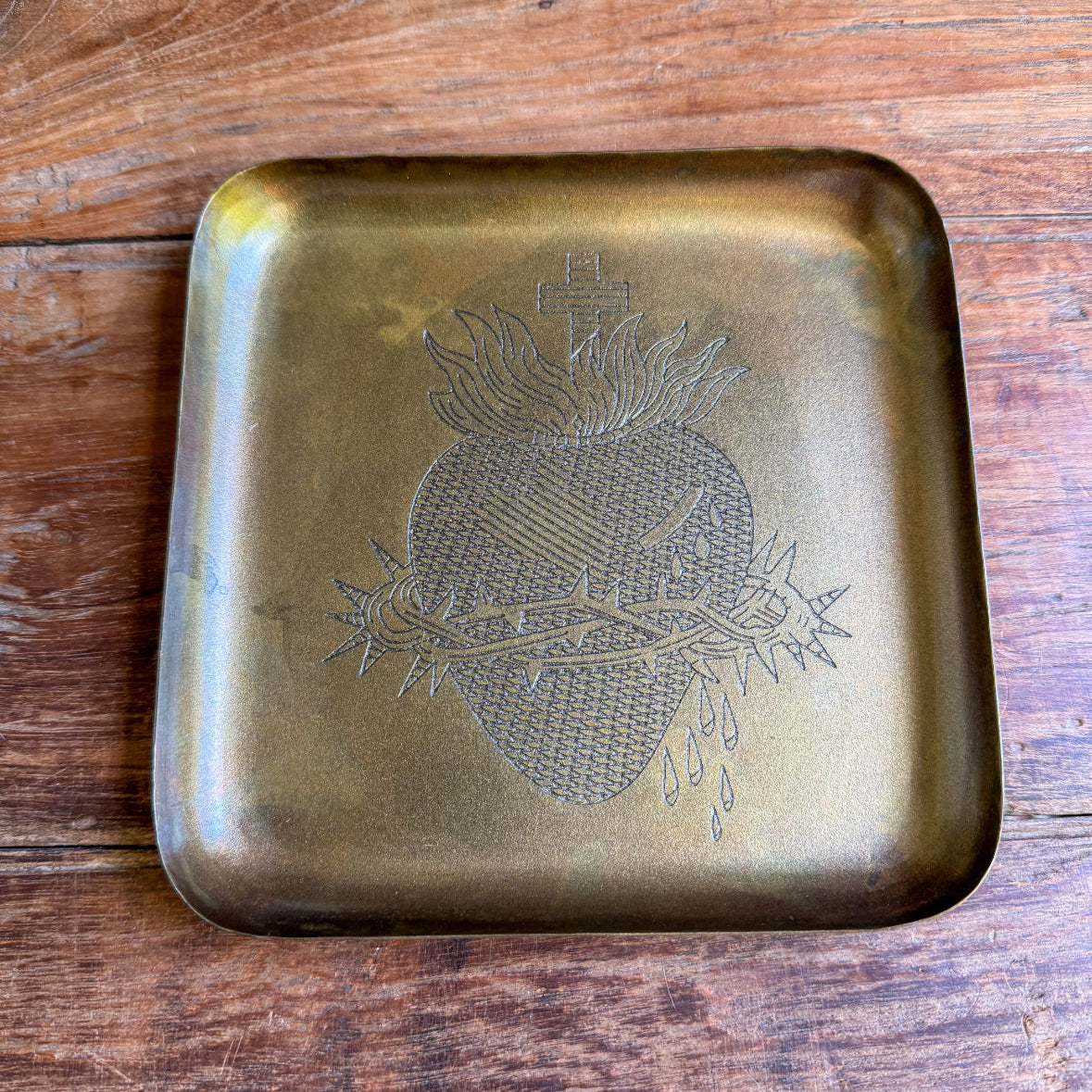 Brass tray with embossed design on a wooden surface