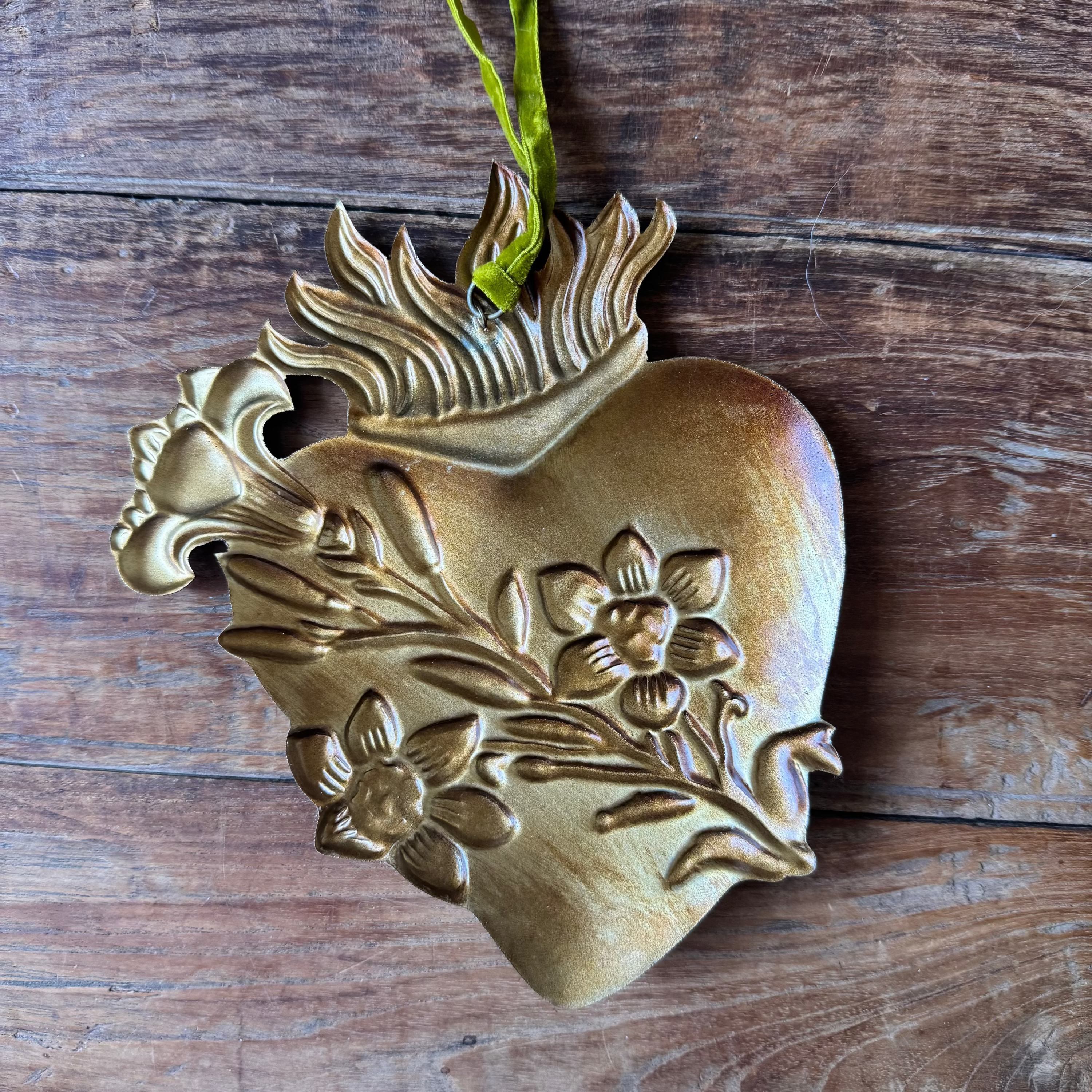 Decorative heart-shaped ornament with floral designs on a wooden surface