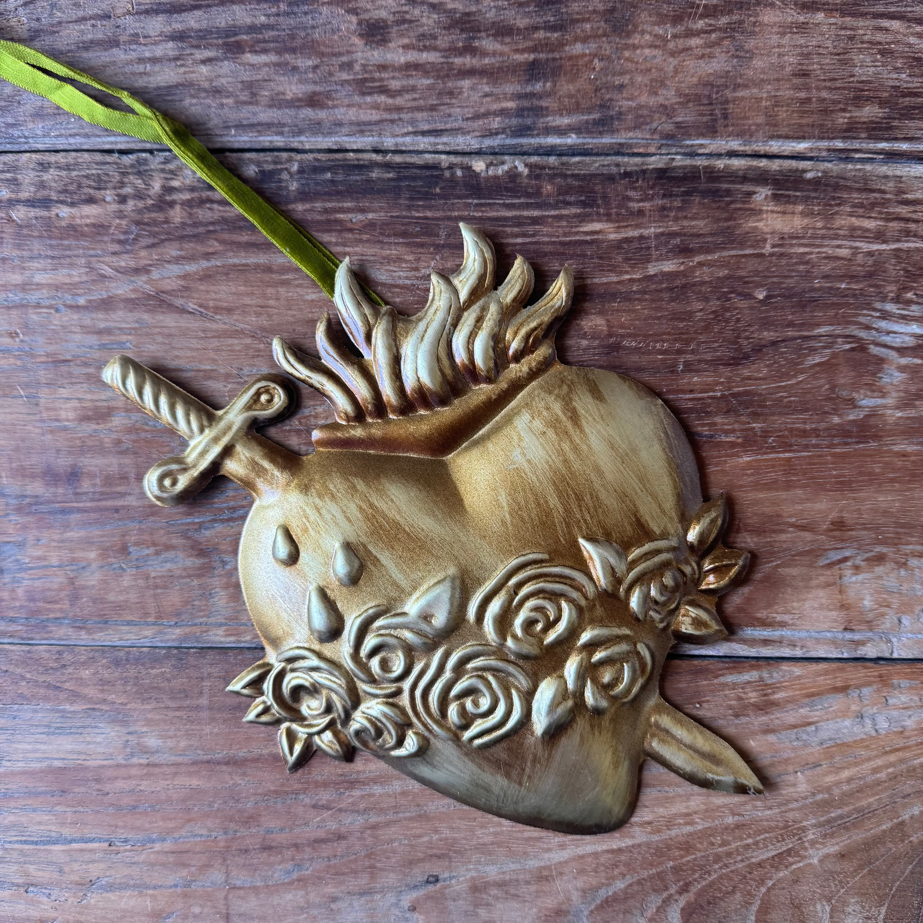Decorative heart-shaped ornament with floral designs on a wooden surface