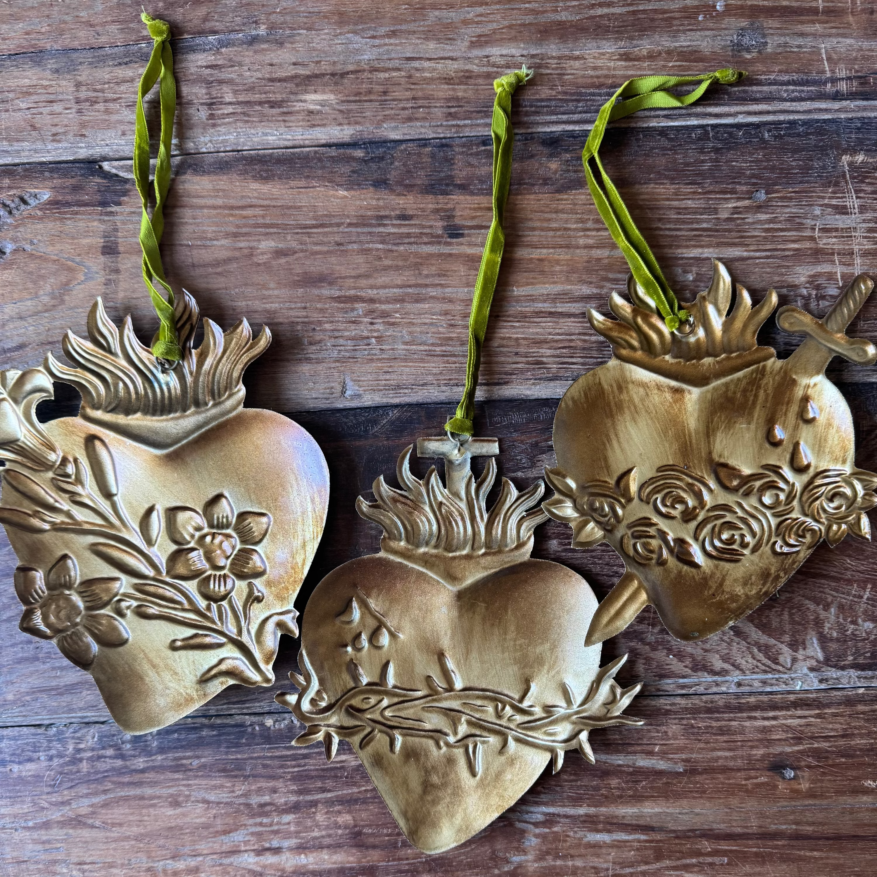 Three gold heart-shaped ornaments on a wooden surface