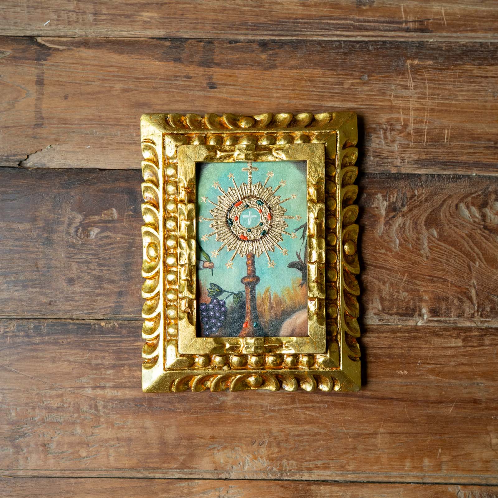 Decorative gold frame with a colorful central design on a wooden background