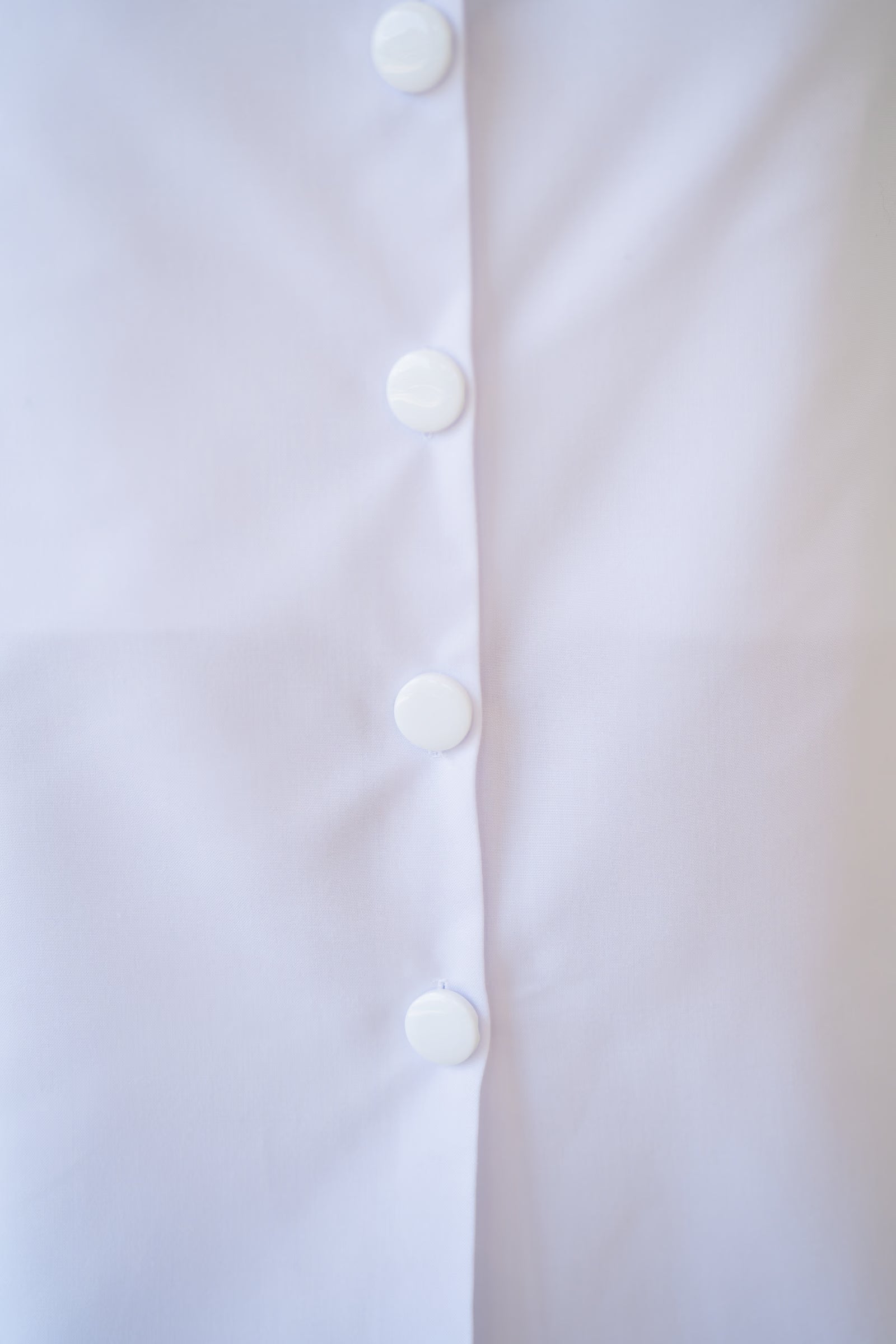 Close-up of a white shirt with buttons on a light background